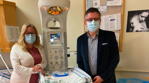 A doctor and patient wearting masks are shown in a hospital room. 