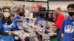 Teens are shown interacting with displays at a STEM event. 
